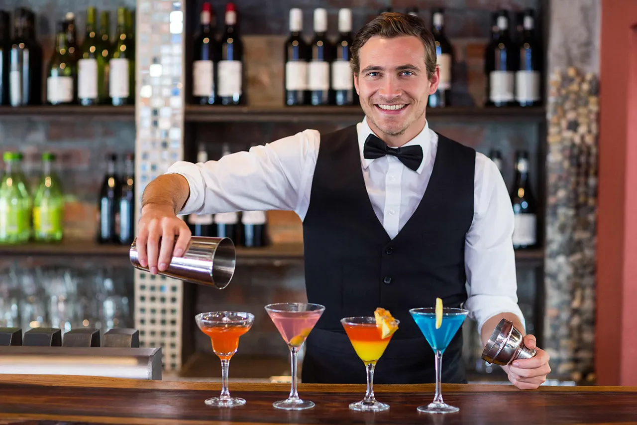 Male bartender with four martinis